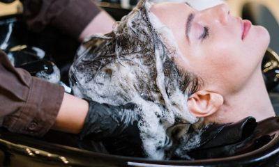 Professional hair stylist washing woman's hair in a modern salon setting.