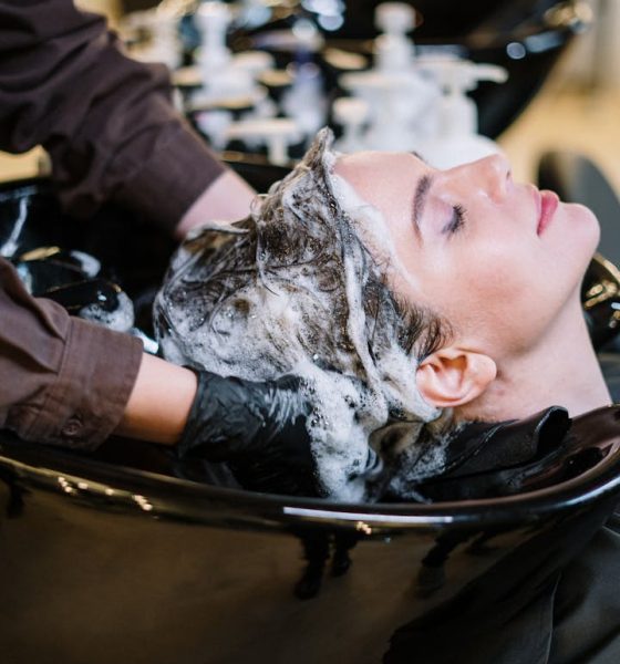 Professional hair stylist washing woman's hair in a modern salon setting.
