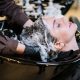 Professional hair stylist washing woman's hair in a modern salon setting.